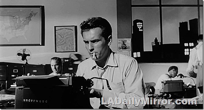 Man smoking a cigarette and writing at a typewriter. 